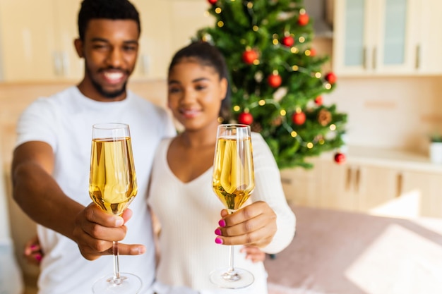 Pareja feliz sosteniendo copas de champán y celebrando el año nuevo en casa