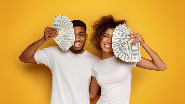 Una pareja feliz sosteniendo un montón de billetes de dinero