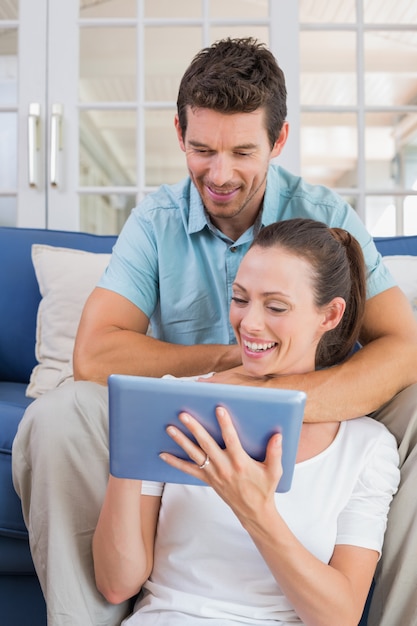 Pareja feliz con tableta digital en el sofá