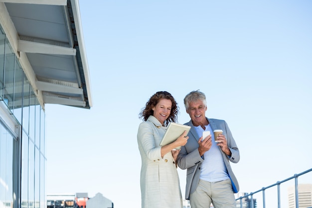 Pareja feliz con tableta digital y teléfono móvil