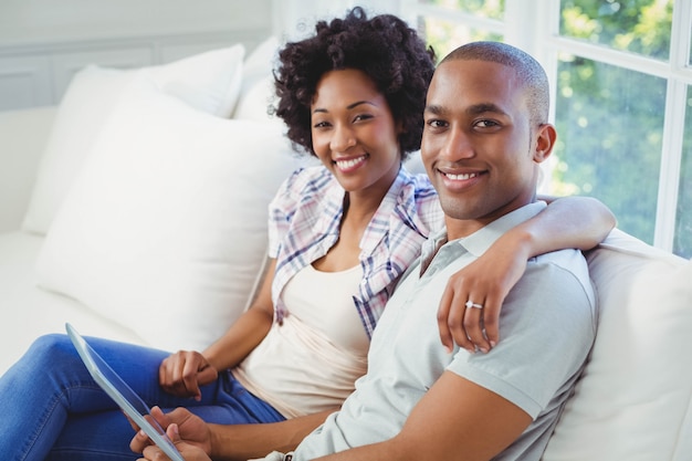 Pareja feliz con tableta en el sofá de la sala de estar