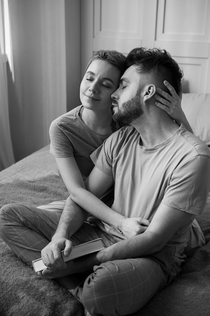 Foto pareja feliz de tiro completo sentada en la cama