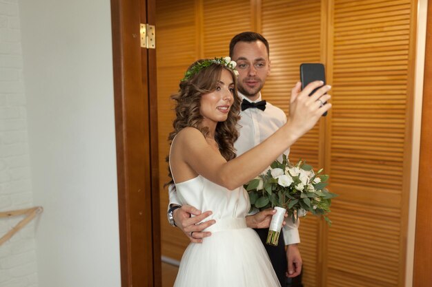Foto una pareja feliz tomando una selfie durante la ceremonia de la boda