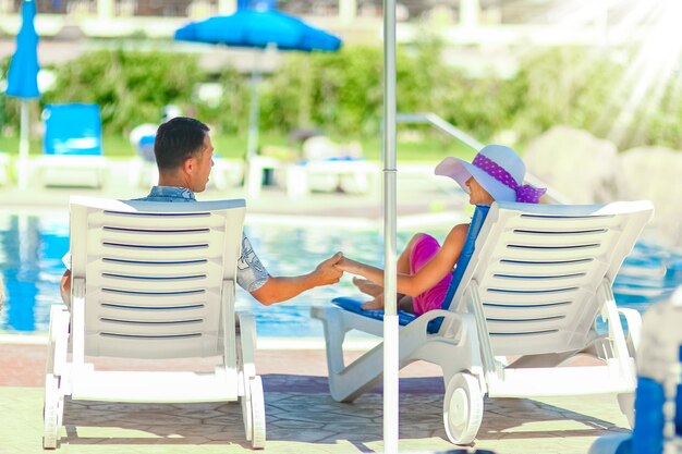 Pareja feliz en tumbonas junto a la piscina junto al mar