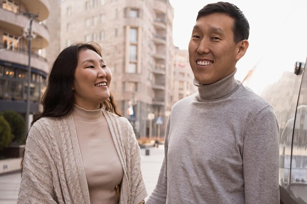 Una pareja feliz de turistas asiáticos adultos caminando por la ciudad.