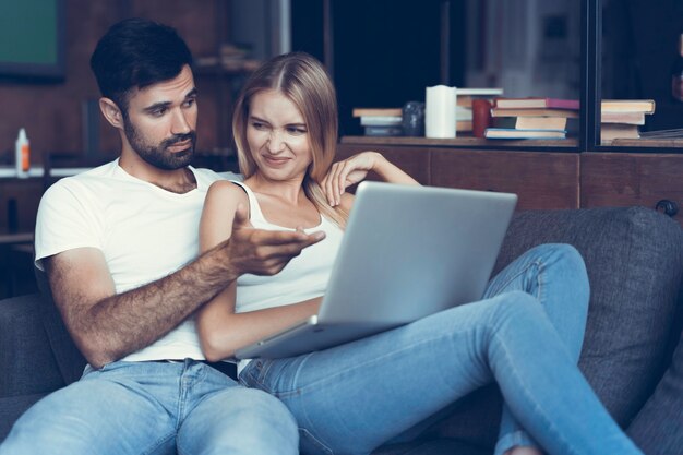 Pareja feliz usando una computadora portátil en el sofá.