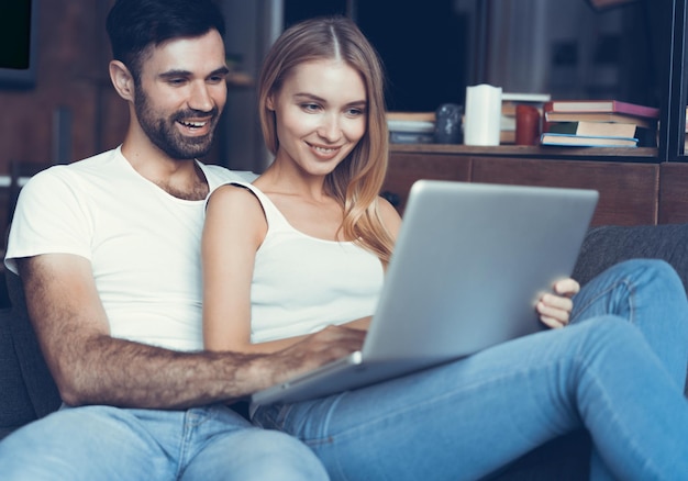 Pareja feliz usando una computadora portátil en el sofá