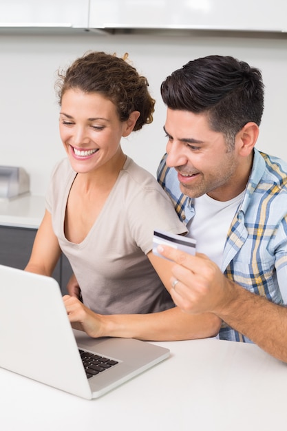 Pareja feliz usando laptop juntos para comprar en línea