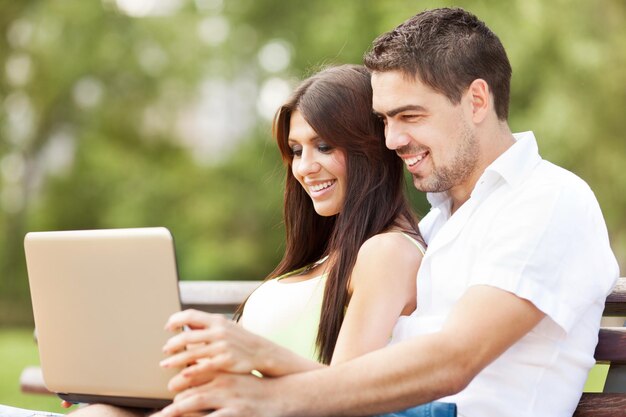 Pareja feliz usando laptop en la naturaleza