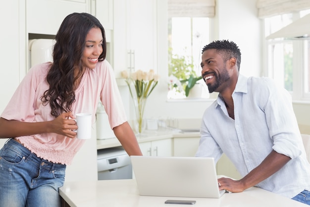 Pareja feliz usando su computadora portátil en el desayuno