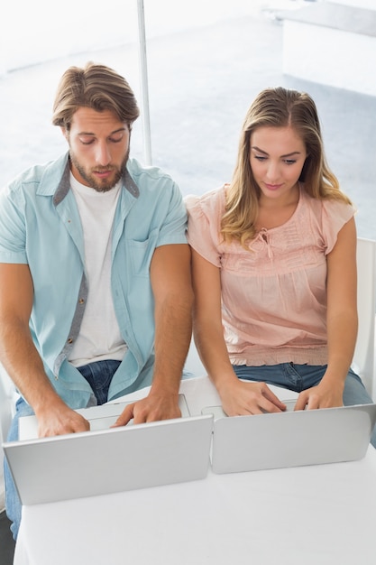 Pareja feliz usando sus computadoras portátiles