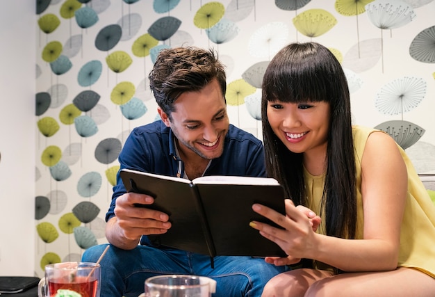 Foto pareja feliz viendo las redes sociales en un cuaderno en el bar. están estudiando o trabajando.