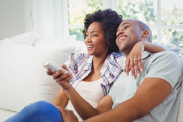 Pareja feliz viendo televisión en el sofá