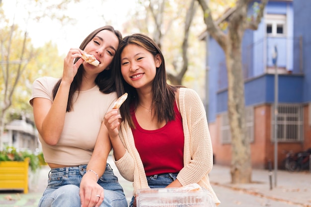 Pareja femenina compartiendo bollos dulces en un parque de la ciudad