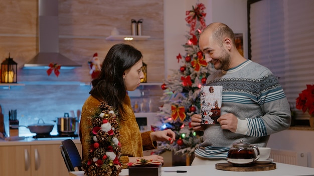 Pareja festiva firmando la tarjeta de Navidad para la festividad navideña