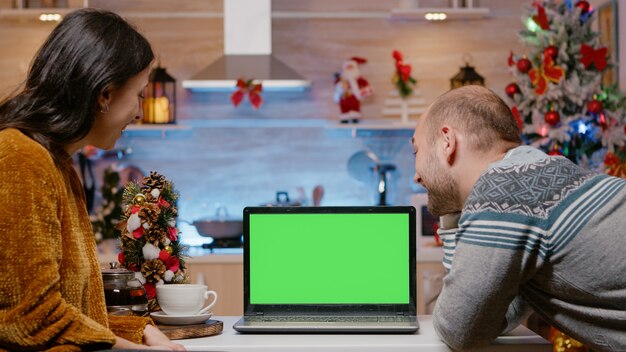 Pareja festiva mirando la pantalla verde horizontal en portátil