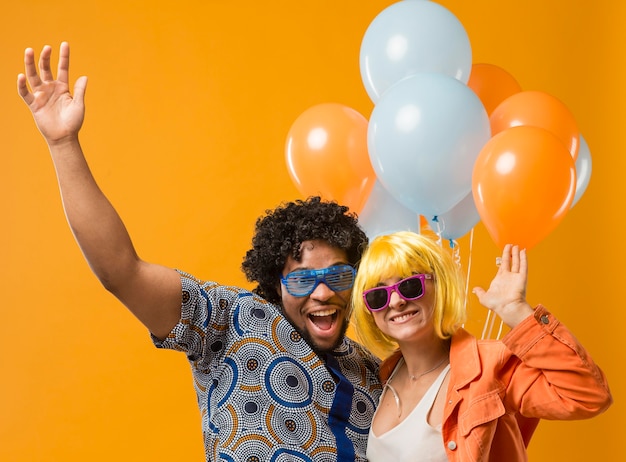 Pareja en fiesta divirtiéndose y sosteniendo globos