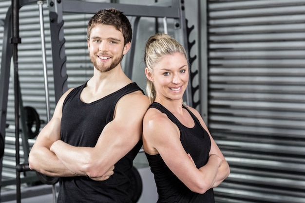 Pareja en forma con el brazo cruzado en el gimnasio crossfit