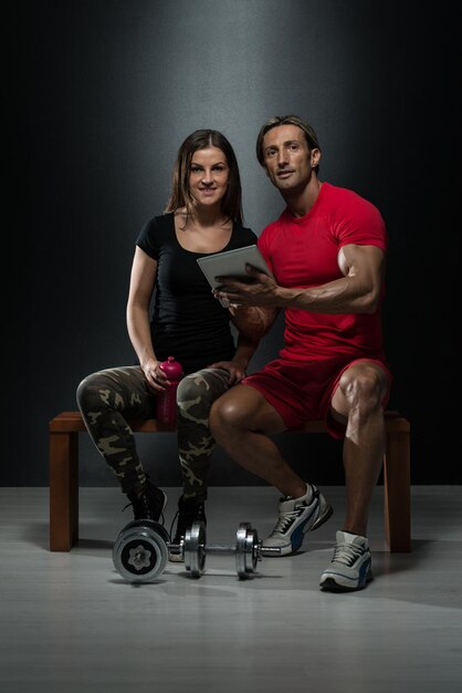 Una pareja en forma mirando una mesa digital en un estudio sobre un fondo negro