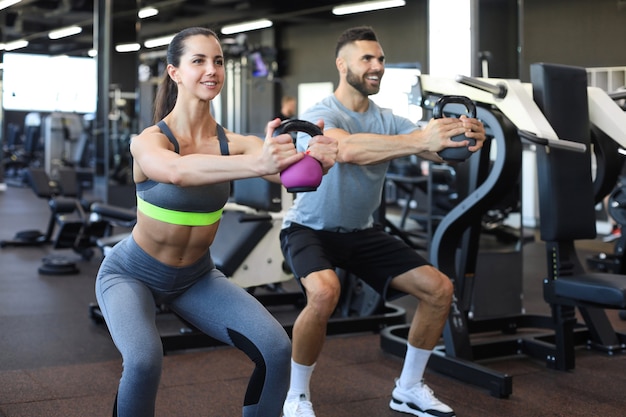 Pareja en forma y musculosa se centró en levantar una pesa durante una clase de ejercicios en un gimnasio.