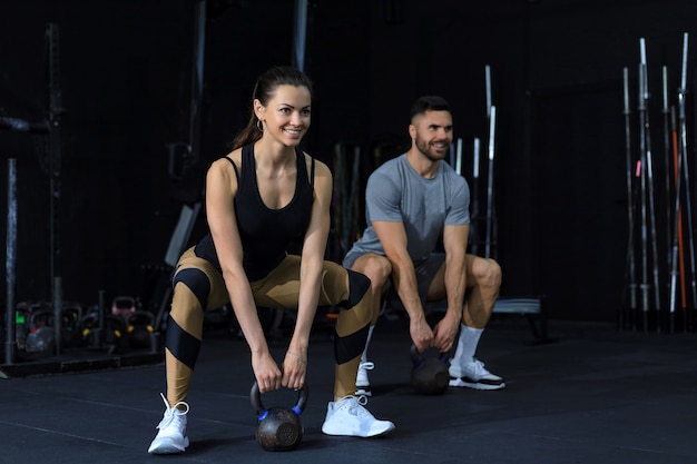 Pareja en forma y musculosa se centró en levantar una pesa durante una clase de ejercicios en un gimnasio.