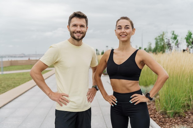 Foto pareja en forma posando con confianza después de una sesión de entrenamiento al aire libre con un parque y nublado