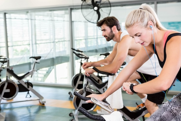 Pareja en forma usando bicicletas de ejercicio en el gimnasio