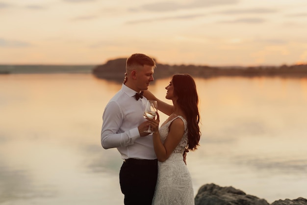 Una pareja frente a un lago con un atardecer de fondo