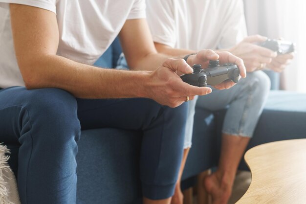 Pareja con gamepads está jugando una consola de videojuegos en casa