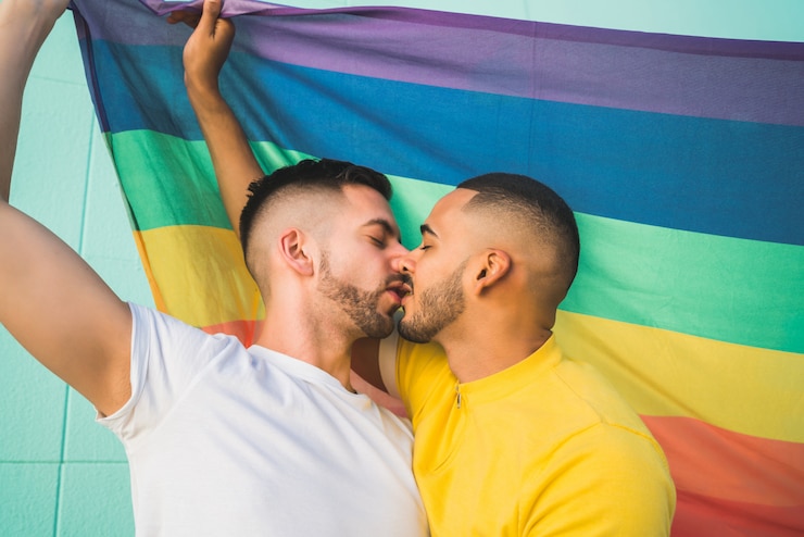 Foto pareja gay abrazando y mostrando su amor con la bandera del arco iris