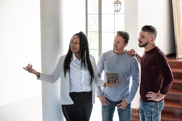 Foto pareja gay con agente de bienes raíces mujer afroamericana en casa nueva