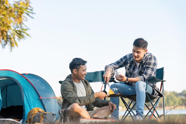 Una pareja gay asiática feliz acampando juntos en un bosque. Viaje romántico de vocación. Concepto LGBT.