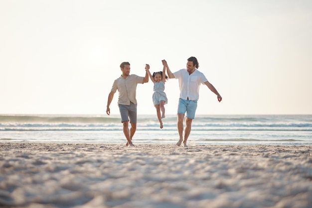 Pareja gay jugando y tomándose de la mano con la familia en la playa para apoyar las vacaciones junto al mar y viajar Vacaciones de verano y amor con hombres y niños en la naturaleza para la felicidad lgbtq y la unión