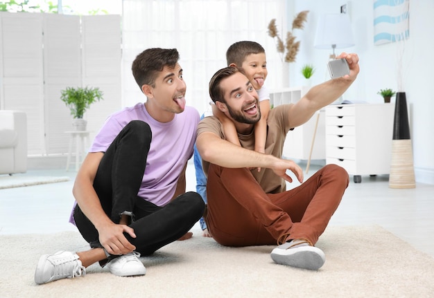 Pareja gay masculina con hijo adoptivo tomando selfie Concepto de adopción