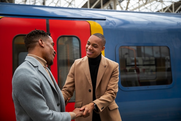 Foto una pareja gay tomados de la mano en la estación de tren durante una cita