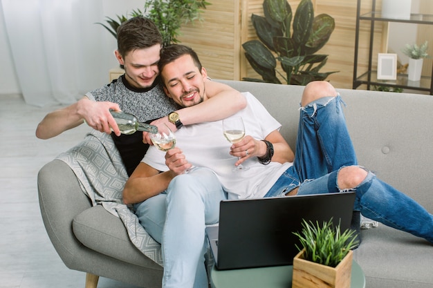 Pareja de gays tomando una copa de vino blanco en su sala de estar