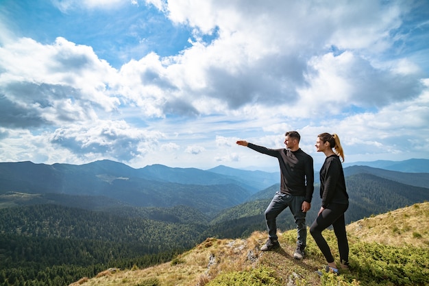 La pareja gesticulando en la montaña con un pintoresco celaje