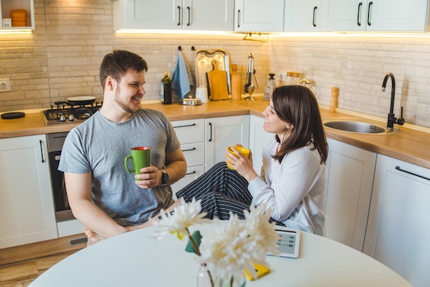 Pareja hablando en la cocina por la mañana bebiendo té