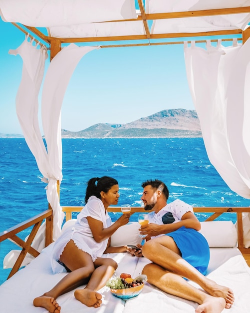 Una pareja hablando mientras se relajan en la cama en un barco contra un cielo despejado