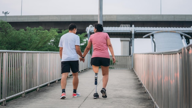 Una pareja haciendo ejercicio en un parque Una mujer con equipos protésicos hace ejercicio afuera