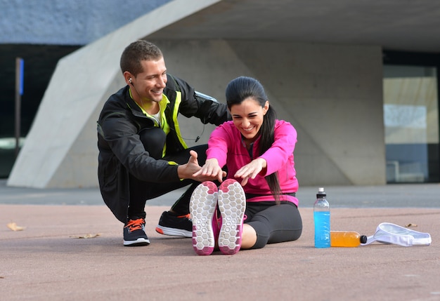 Pareja haciendo estiramientos después de correr por la ciudad