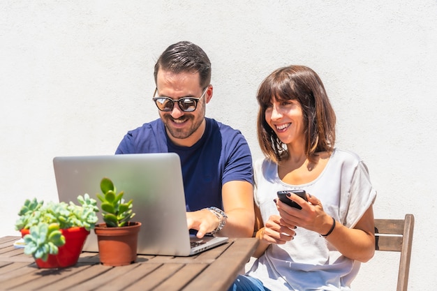 Foto una pareja haciendo una videollamada con amigos en la computadora en la terraza