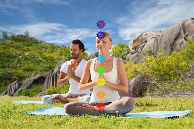 Foto pareja haciendo yoga en la postura del loto con siete chakras