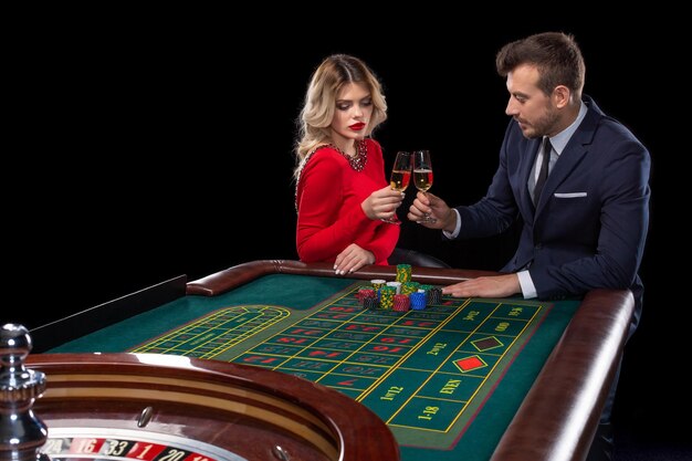 Pareja hermosa y bien vestida jugando a la ruleta en el casino