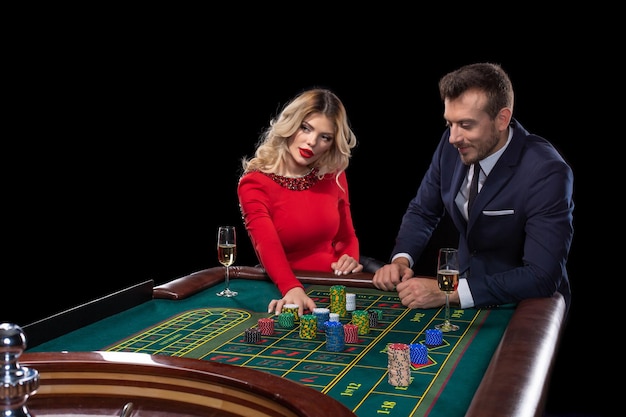 Pareja hermosa y bien vestida jugando a la ruleta en el casino