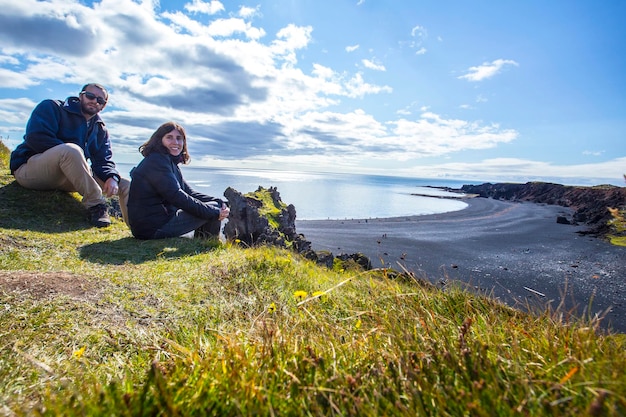 Una pareja en la hermosa playa de piedra negra desde arriba de la costa de Snaefellsnes, Islandia