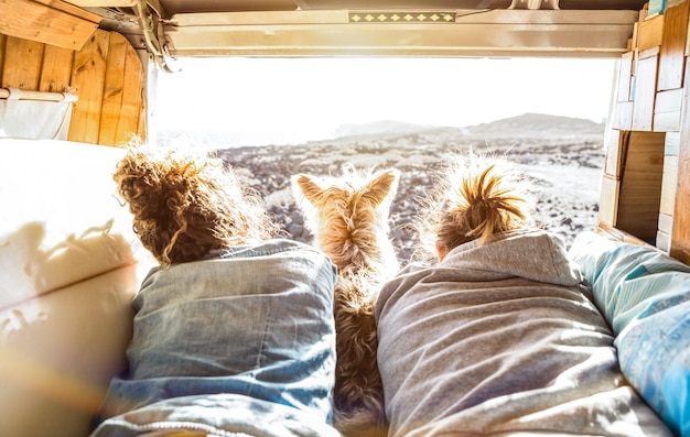 Pareja hipster con lindo perro viajando juntos en transporte van vintage