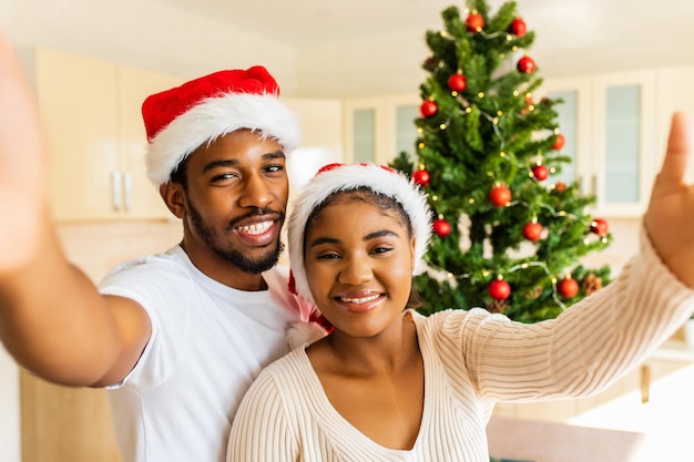 Pareja hispana latina tomando una foto selfie en cámara cerca del árbol de navidad en casa