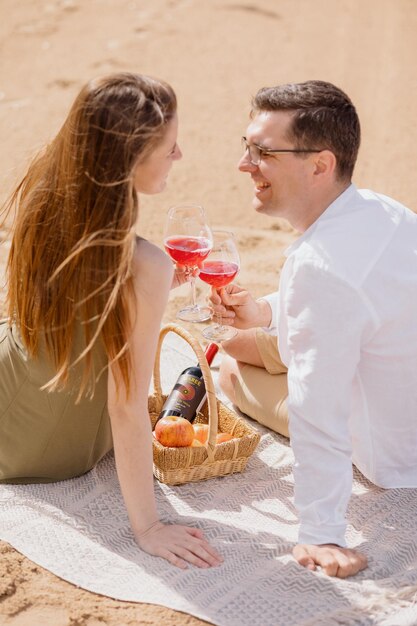 Una pareja de un hombre y una mujer caminan por la playa y hacen un picnic en la arena de