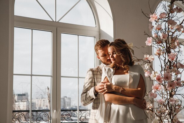 pareja hombre y mujer cerca de la ventana en el día de la boda retrato familiar Día de San Valentín
